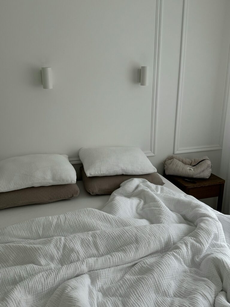 A cozy bed with a soft knitted blanket in neutral tones, creating a peaceful and warm aesthetic bedroom look