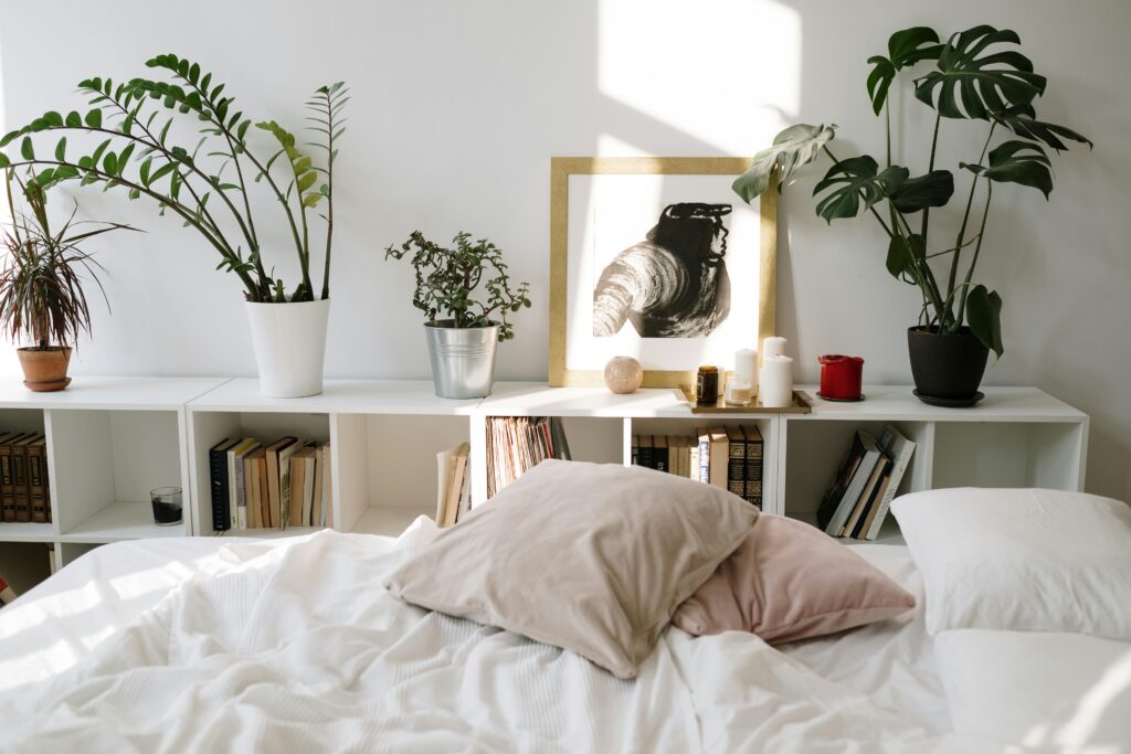 Cozy bedroom with soft white bedding, indoor plants, and natural light creating a calm and refreshing decor
