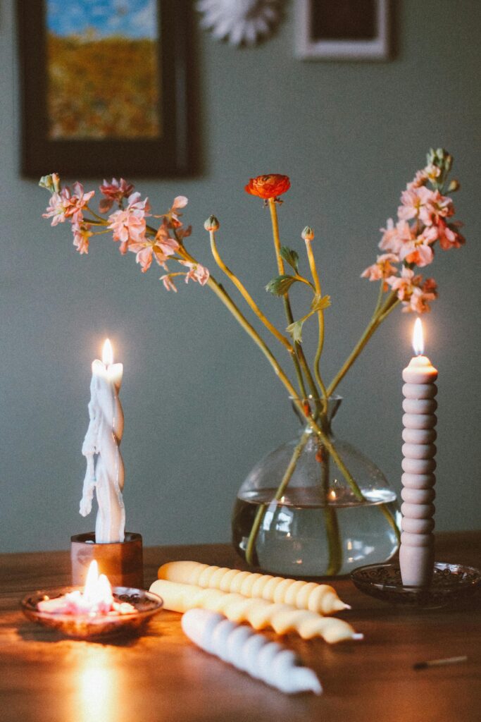 Minimal bedroom decor with soft candlelight, flowers in a vase, and warm cozy ambiance on a wooden table