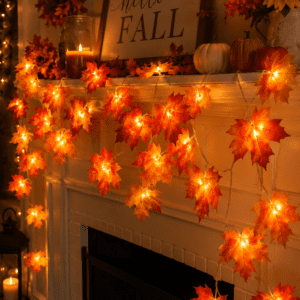 Fireplace mantel decorated with glowing maple leaf string lights, pumpkins, candles, and cozy fall decorations.