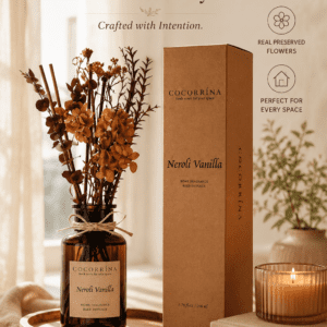 Luxury Neroli Vanilla reed diffuser with preserved flowers in an amber glass bottle, creating an elegant home fragrance display in a cozy living room.