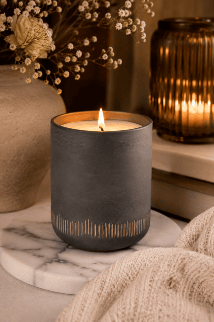 Stylish black ceramic scented candle displayed on a marble tray with soft lighting for modern cozy home decor inspiration.