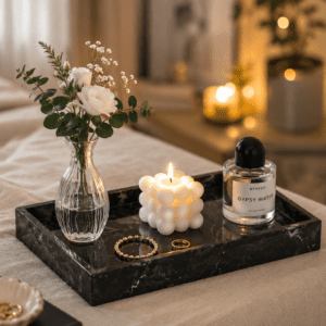 Luxury black marble decorative tray featuring a glass flower vase, bubble candle, perfume bottle, and jewelry styled on a cozy bedroom bench with soft ambient lighting.