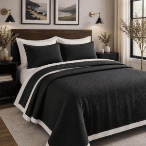 Black and white reversible quilt set on a wooden bed in a modern farmhouse bedroom featuring black nightstands, warm wall sconces, neutral decor, and cozy minimalist styling.