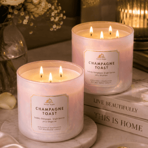 Luxury White Barn Champagne Toast triple wick soy wax candle in an iridescent glass jar displayed with roses, marble tray, books, and elegant home décor.