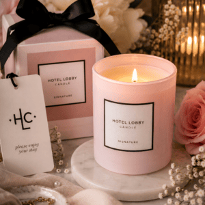 Luxury Hotel Lobby Signature scented candle in a soft blush pink glass jar with elegant gift box, fresh flowers, marble tray, and cozy home decor.