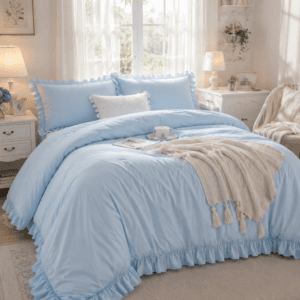 Luxury light blue ruffled bedding set styled in a bright cottage-inspired bedroom with soft white furniture, cozy knit throw blanket, and elegant farmhouse decor.