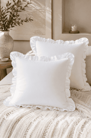 White ruffle throw pillow covers styled on a cozy neutral sofa with a chunky knit blanket, candle, and modern farmhouse living room décor.