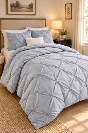 Light blue geometric pintuck comforter with matching pillows styled in a warm elegant bedroom with neutral decor and natural lighting.