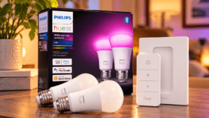 Philips Hue color changing A19 smart LED bulbs displayed with black retail packaging, white dimmer switch and matching wall mount.