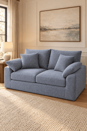 Blue gray upholstered loveseat sofa with deep cushions and matching pillows styled in a warm neutral modern living room interior.